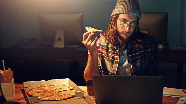 在屏幕前吃披萨。