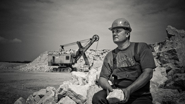 رجل يجلس ويحمل صخرة كبيرة في موقع البناء
