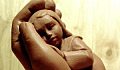 a clay sculpture of a child being held in a supportive hand