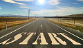 an open road with the word start written on the pavement in huge letters