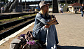 woman sitting on her suitcases at a railroad station