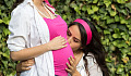a young girl kissing the belly, and unborn child, of her pregnant mother