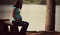 pregnant woman sitting with her hands on her belly