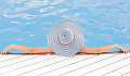 Women laying in the pool with her arms on the edge, wearing a sun hat