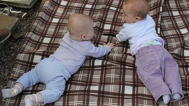 dua bayi berkomunikasi di atas selimut