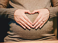 woman's hands forming a heart shape on top of her womb
