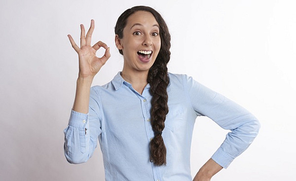 woman with a big smile and fingers in an "a-ok" symbol