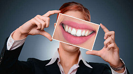 a woman holding up an enlarged photo of her teeth