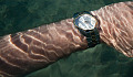 an arm wearing a wristwatch under water